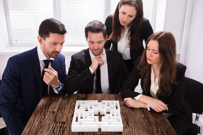 Businesspeople Trying To Solve Maze Puzzle